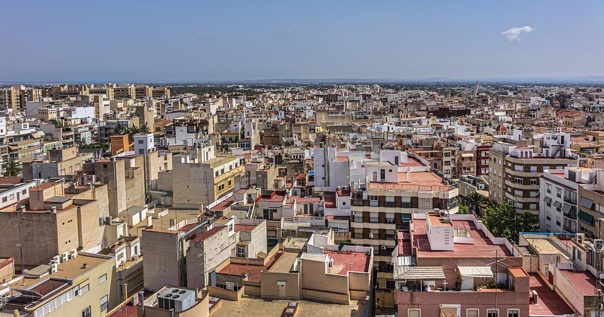 Vista panorámica de numerosos edificios con azoteas, terrazas y balcones bajo un cielo azul.